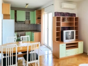 Cozy living space with a kitchenette, dining table, and entertainment unit, offering a comfortable retreat with a sliding door to an outdoor area.