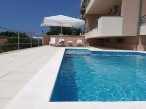 Relax by the pool with lounge chairs and a table under shaded umbrellas.