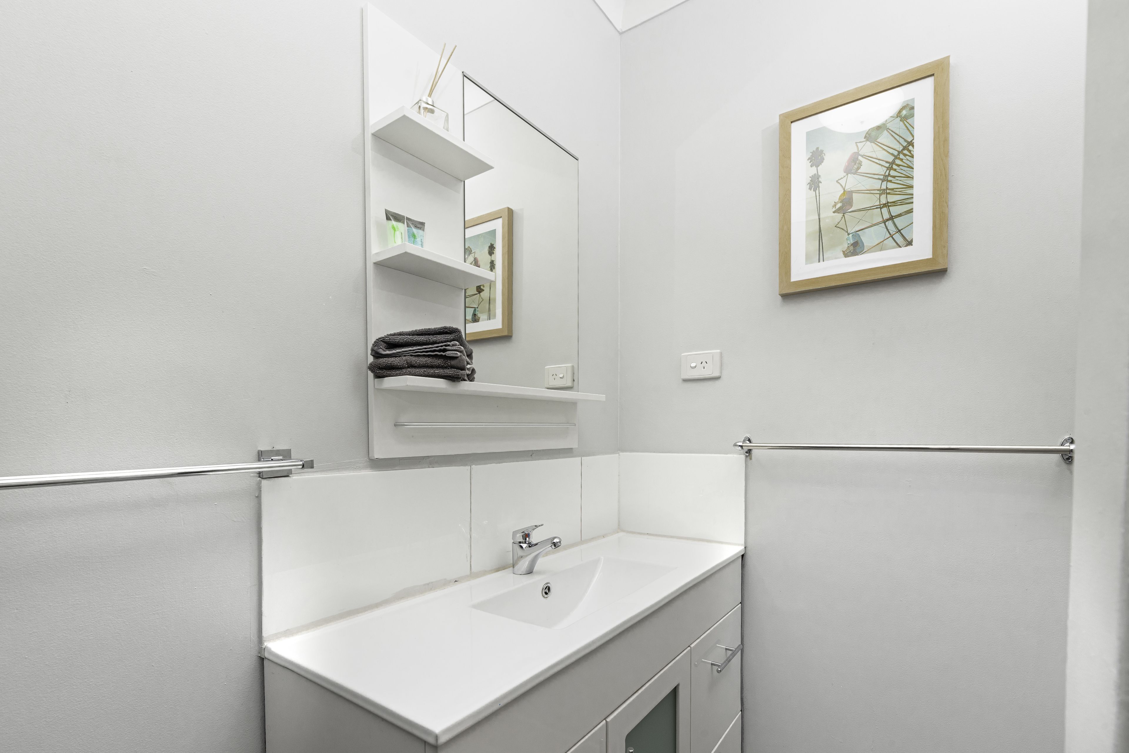 Ein modernes Badezimmer mit Waschbecken, Spiegel und Ablageflächen.