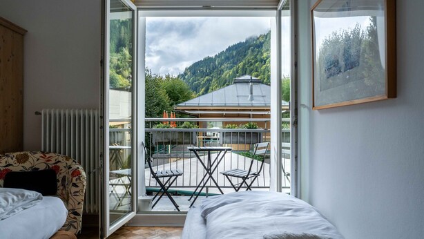 Une chambre d’hôtel avec un lit, une chaise et un balcon équipé d’une table et de chaises.