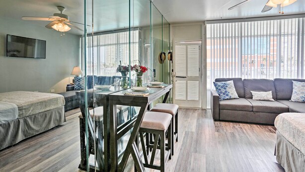 Une pièce moderne comprenant une table à manger, deux tabourets de bar, un canapé et un ventilateur de plafond.