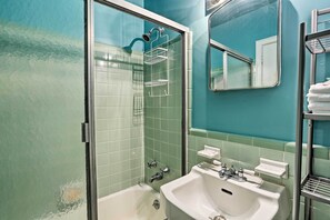 A bathroom with a glass-enclosed shower, a white sink, and a mirror. - Virginia Beach Studio w/ Balcony + Pool View! (Virginia Beach)