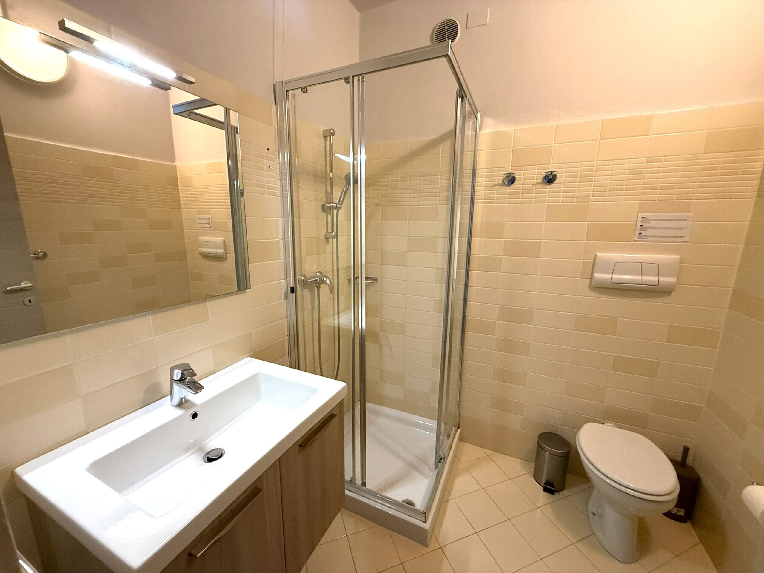 A bathroom with a glass shower enclosure, a sink, and a toilet.