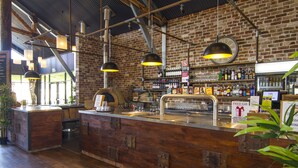 A bar with a wooden counter, hanging pendant lights, and a brick wall. - Dubbo Rhino Lodge (Dubbo)