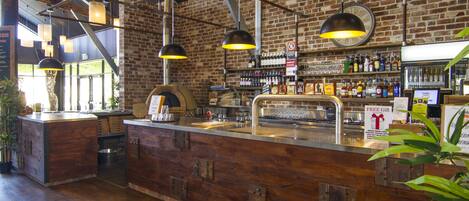 Un bar con mostrador de madera, lámparas colgantes y pared de ladrillo.