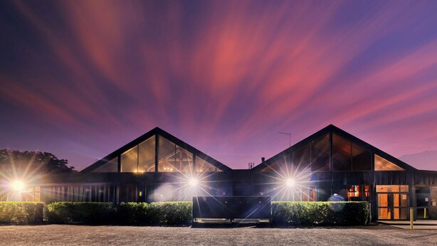 A modern building with a symmetrical design, large windows, and a well-lit entrance. - Dubbo Rhino Lodge (Dubbo)