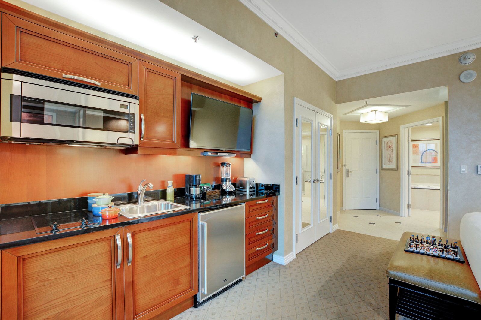 A modern kitchen with wooden cabinets, stainless steel appliances, and a flat-screen TV.