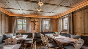 Un interior de madera con una larga mesa y bancos, una cruz en la pared y ventanas amplias.