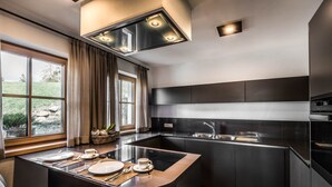 Una cocina moderna con una isla central, muebles oscuros y un amplio ventanal con cortinas.