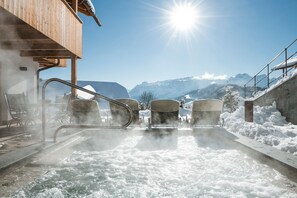 A hot tub with steam rising, surrounded by snow, with a wooden building and mountains in the background. - MOUNTAIN CHALET PIA Dolomites - Alta Badia (La Valle)
