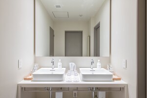 Ein modernes Badezimmer mit zwei Waschbecken, einem großen Spiegel und einem Handtuchhalter.