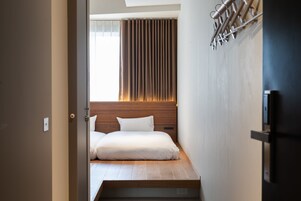 Ein modernes Schlafzimmer mit einem Holz-Kopfteil, einem Bett mit weißen Bettwäsche und einem Fenster mit Vorhängen.