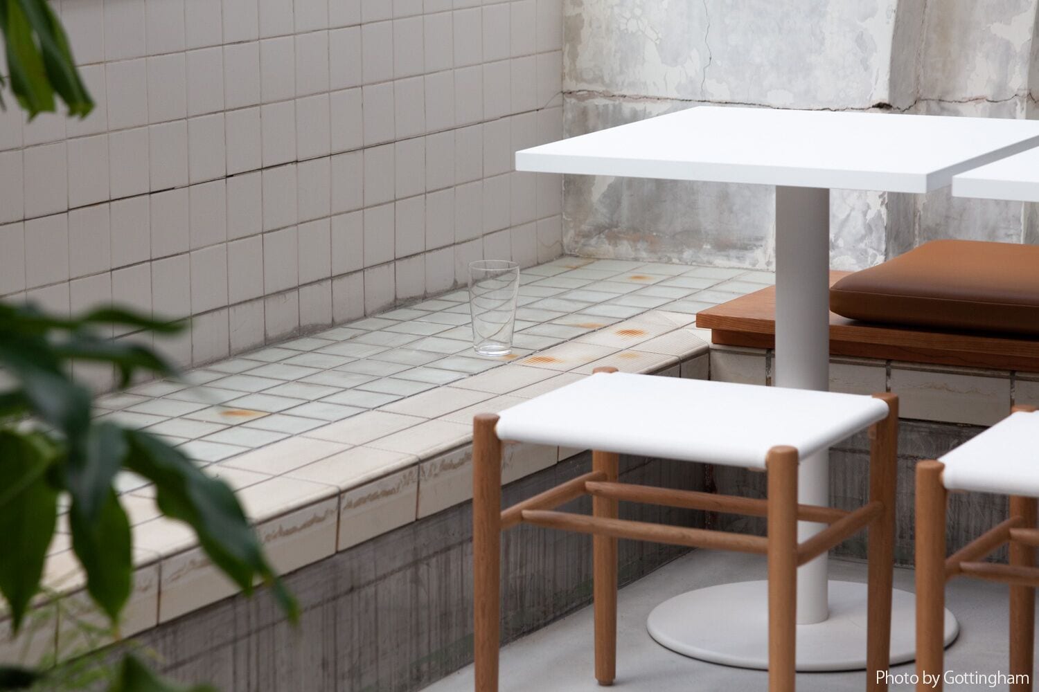 A modern interior with a tiled floor, white tables, and wooden chairs.