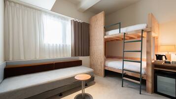 Ein kleines Zimmer mit Etagenbett, einem Schreibtisch mit Lampe und einer gepolsterten Sitzbank.