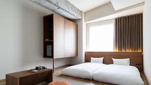 A modern bedroom with a bed, a wooden bench, a small ottoman, and a built-in TV shelf.