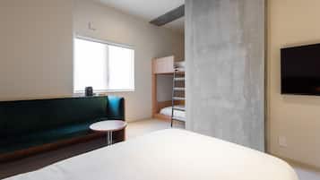 A modern hotel room with a large bed, a green sofa, a small round table, a bunk bed, and a TV mounted on the wall.