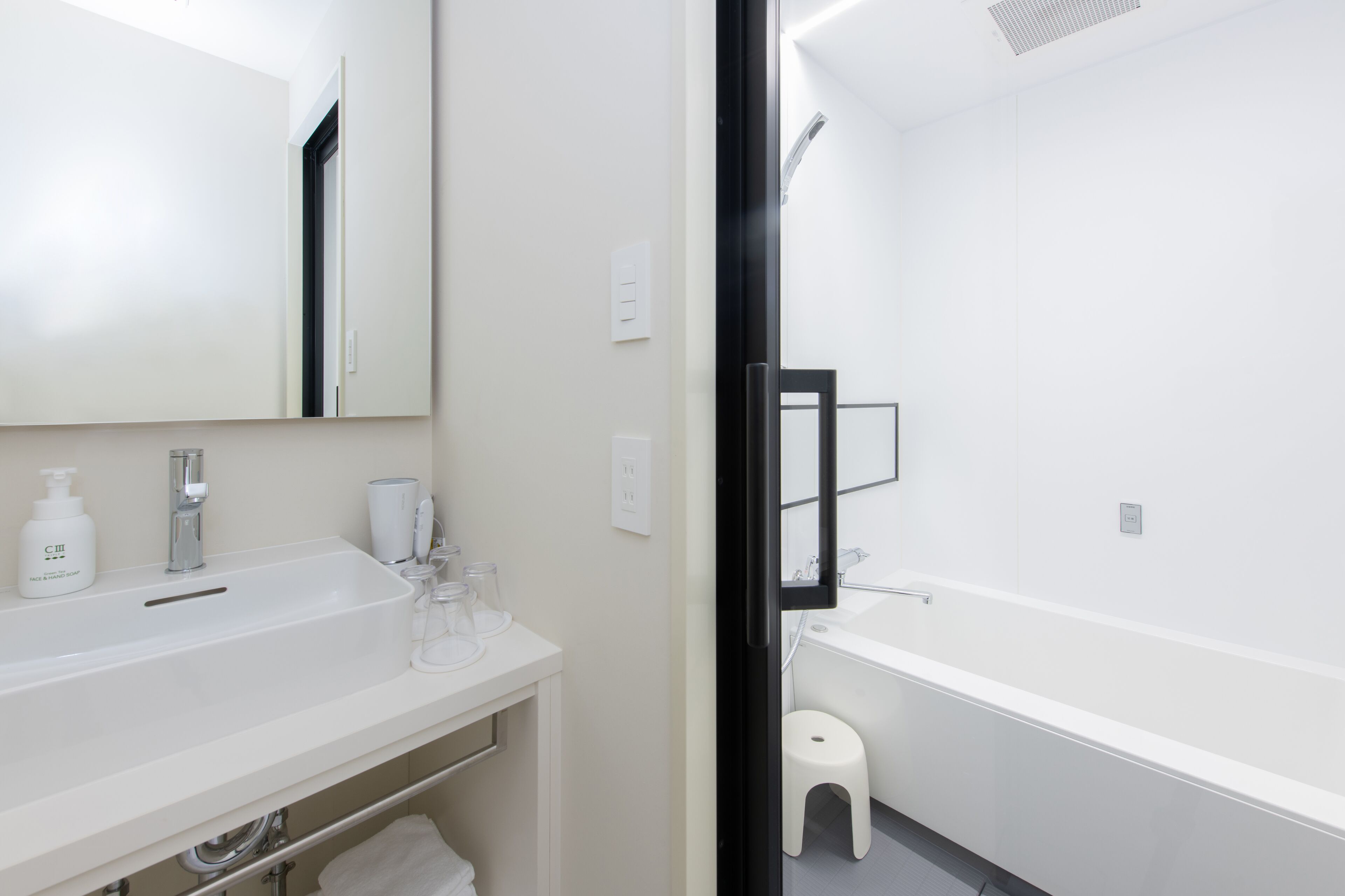 A modern bathroom with a white sink, mirror, and bathtub.