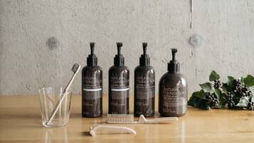 Four bottles of natural foundation superlative organic bodycare, a clear glass, and a white brush on a wooden surface.