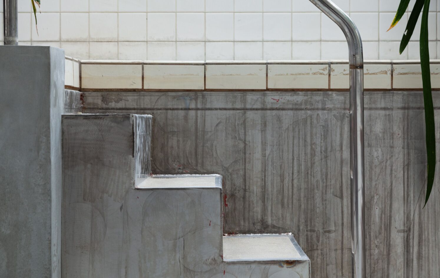 A set of metal steps leading up to a tiled wall.