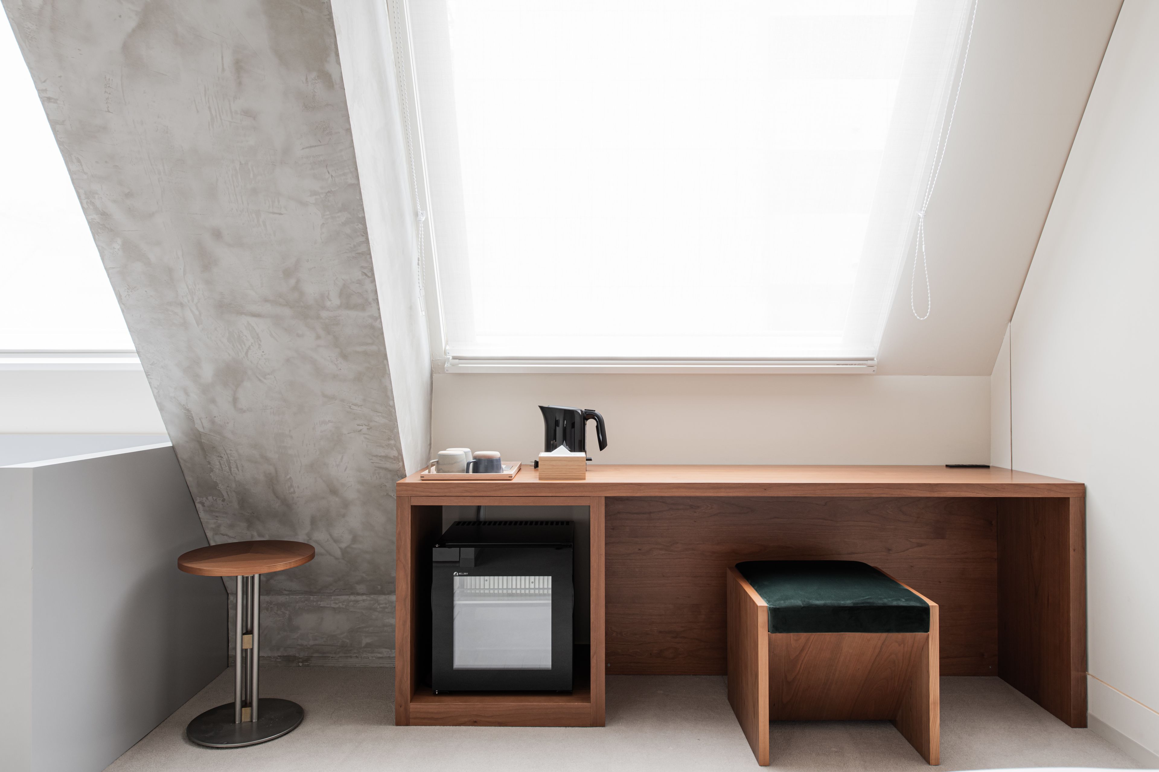 A modern, compact workspace with a wooden desk, a small stool, and a built-in printer.