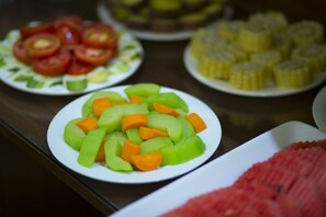 Une table de buffet proposant divers assortiments de fruits, notamment du melon, des tomates et de l’ananas.