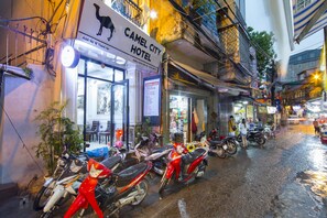 Un hôtel appelé « Camel City Hotel », avec une enseigne, des motos garées et une rue mouillée.