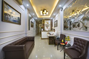 A hotel reception area with a marble counter, leather seating, and a framed photograph on the wall. - Camel City Hotel (Hanoi)