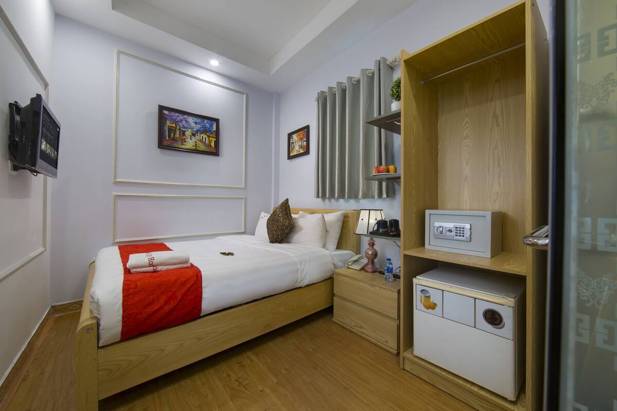 A neatly arranged hotel room with a bed, bedside table, and a built-in safe.
