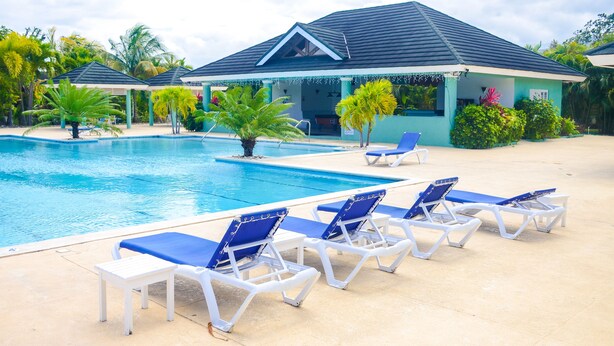 A swimming pool with lounge chairs and a covered pavilion. - Tranquillity at The Palms (St. Ann's Bay)