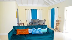 A teal sofa with three cushions, a dining table with chairs, and a wooden side table. - Tranquillity at The Palms (St. Ann's Bay)