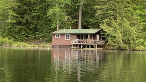 Una cabaña sobre pilotes en un lago, rodeada de bosque denso.