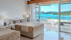 Habitación de hotel moderna con una cama grande, una cama más pequeña y un balcón con vistas al mar.