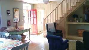 A dining area with a table set for four, a chair, and a sofa. A staircase leads to an upper level. - Comfortable Home in a beautiful part of Dingle Town (Dingle)