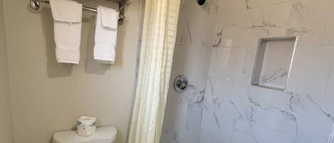 A bathroom with a toilet, a bathtub, and a shower curtain.