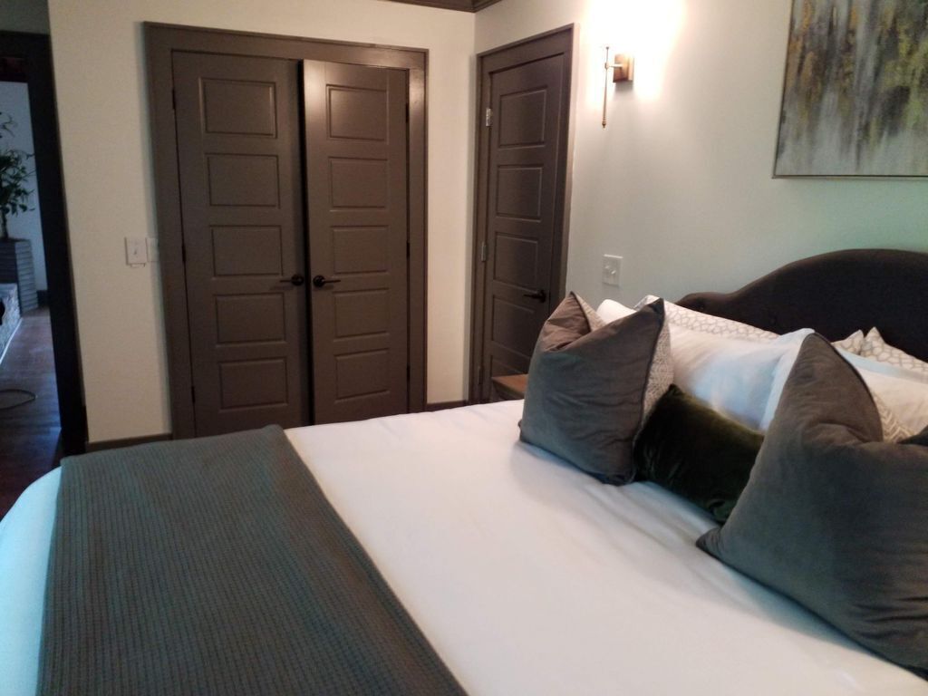 Une chambre d’hôtel avec un grand lit, deux portes et un luminaire fixé au mur.