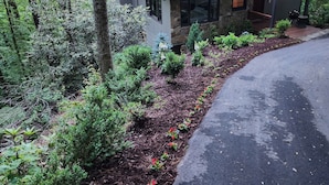 A house with a stone facade, a metal roof, and a garden with various plants and flowers. - Relaxing big sky views early booking discounts for Summer! (Highlands)