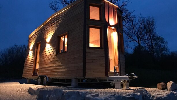 Una cabaña de madera con varias ventanas, una puerta principal y un pequeño porche.