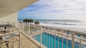 Un balcone con piscina, sedie e vista sull'oceano.
