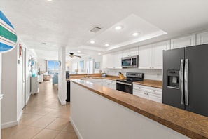 A modern kitchen with white cabinets, a granite countertop, stainless steel appliances, and a central island.