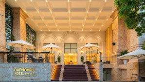 A grand hotel entrance with marble columns, a staircase, and outdoor seating with umbrellas. - Daphovina Hotel (Bac Nha Trang)