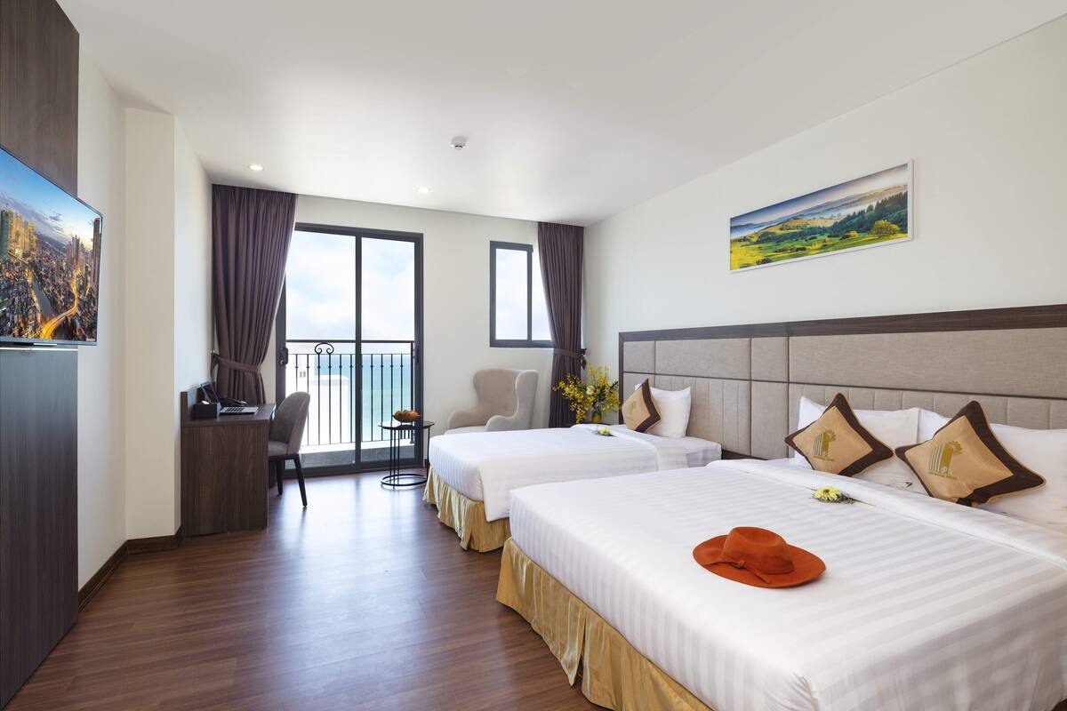 A hotel room with two beds, a desk, and a view of the city.