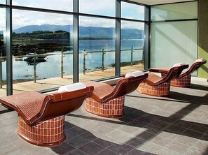 Relax in a serene indoor seating area with a stunning lake view and mountain vistas.