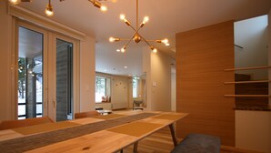 A modern dining area with a long wooden table, benches, and a unique chandelier. - Asanoha (Furano)