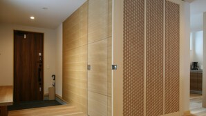 A hotel room with a wooden floor, a sliding door with a patterned design, and a visible exit sign. - Asanoha (Furano)