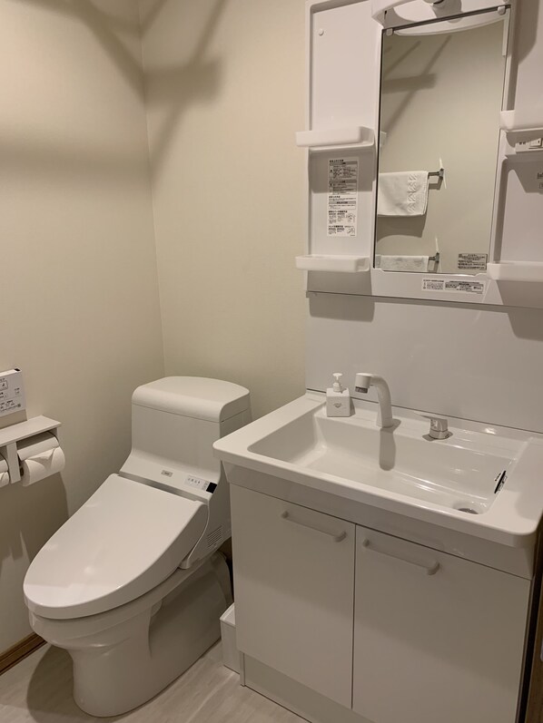A modern bathroom with a toilet, sink, and cabinet. - Hakobune Furano (Furano)