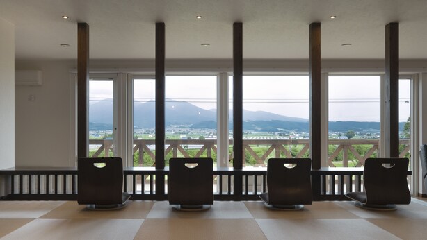 A room with tatami mats, a balcony with a view of mountains, and a row of chairs. - Furano Lookout (Nakafurano)