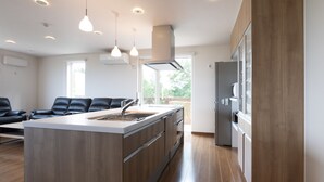A modern kitchen with a central island, built-in appliances, and pendant lighting. - Furano Lookout (Nakafurano)