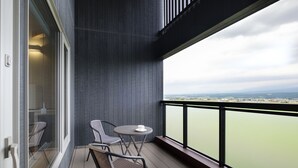 A balcony with two chairs and a table, overlooking a body of water and distant landscape. - Furano Lookout (Nakafurano)