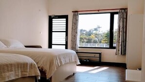 A bedroom with two beds, a window with curtains, a wooden floor, and a ceiling fan. - Summer Homestay (Hengchun)
