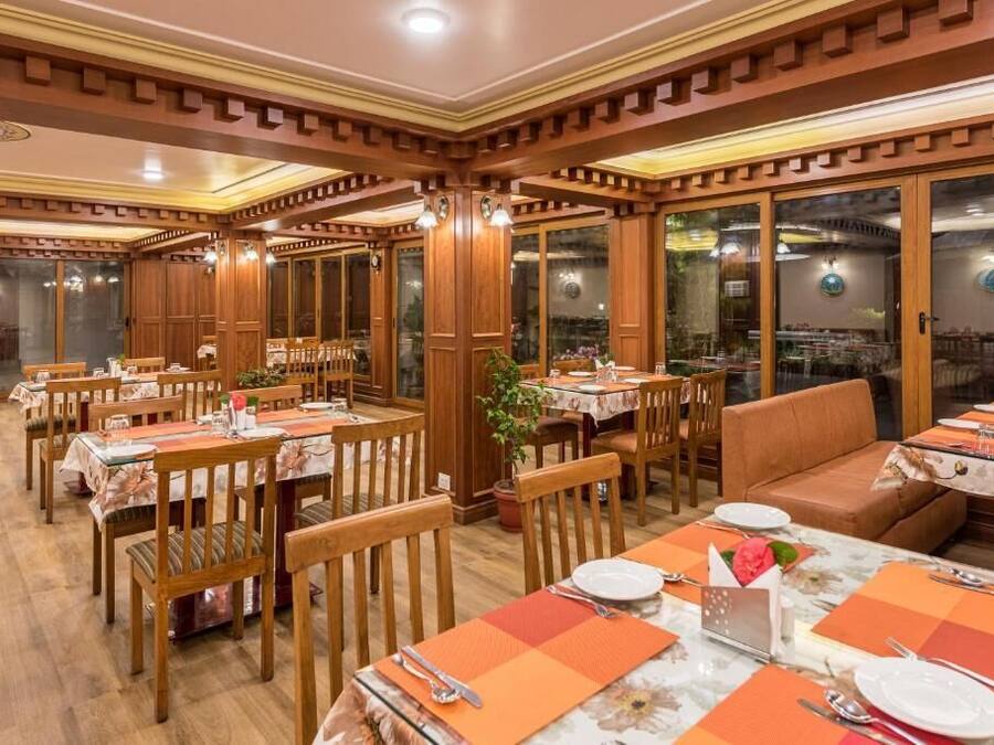 A restaurant with wooden paneling, tables set with orange placemats, and large windows.